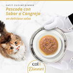 Gato mirando un plato de tarrina de pescado con sabor a cangrejo Catit Cuisine Dinner servido en bandeja de plata con guantes blancos.